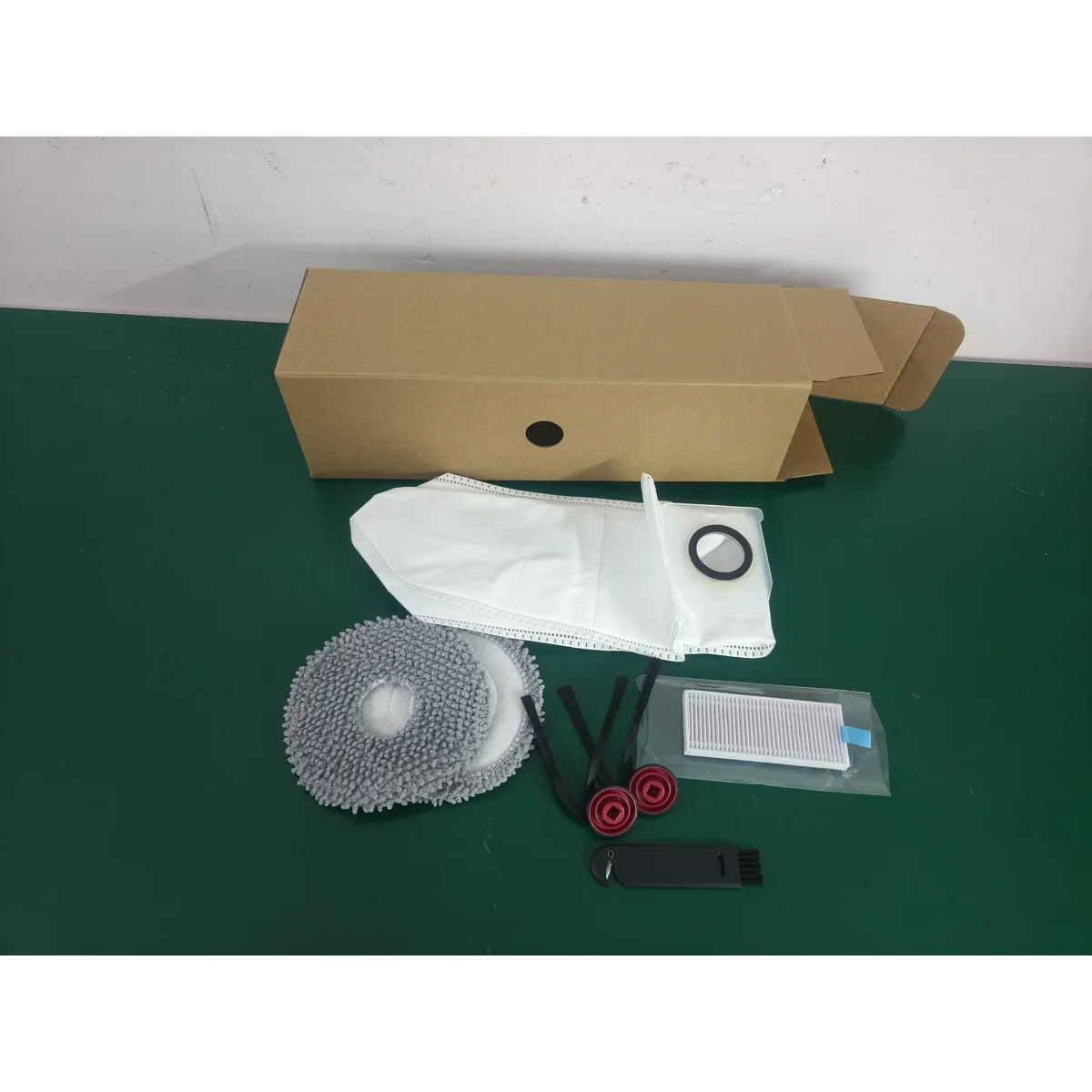 SW75 spare accessories laid out: mop pads, side brush, filter, dust bag and cleaning tool